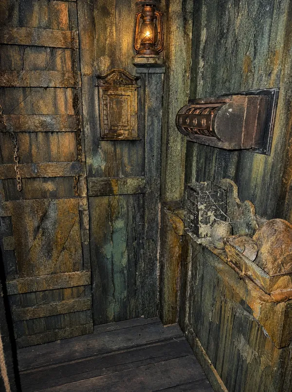 Ecke im Wrack mit Bohlentür, Ketten, Laterne, Wandkästchen und einem Walzenschloss