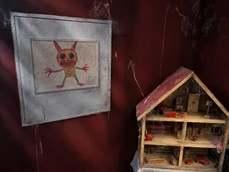 Puppenhaus vor der roten Wand, daneben die große Zeichnung eines kleinen Monsters