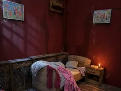 Kinderzimmer mit Bett, Nachttisch und Kinderzeichnungen an der roten Wand